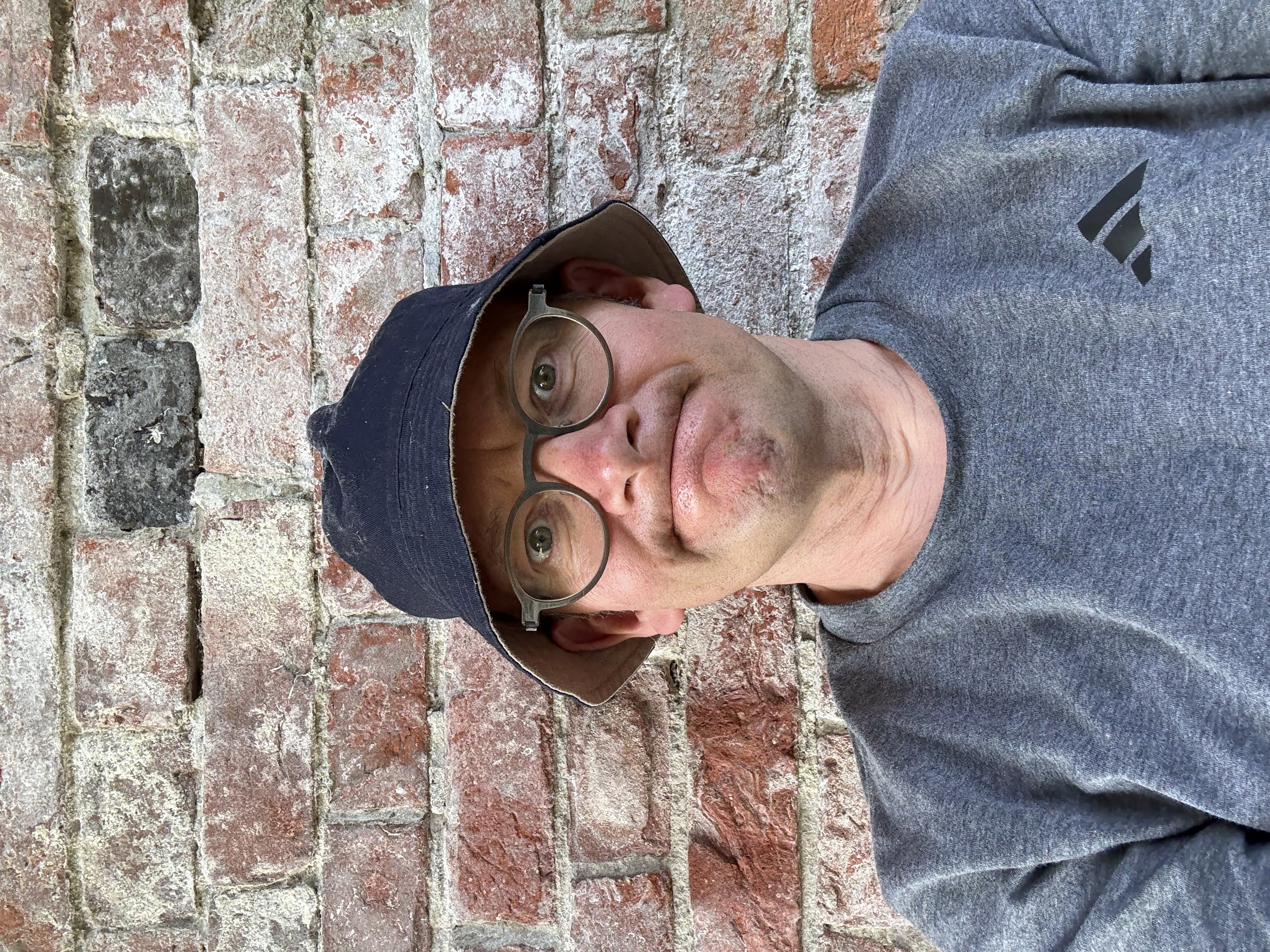 Roger Coleman sitting under a bridge wearing a hat.